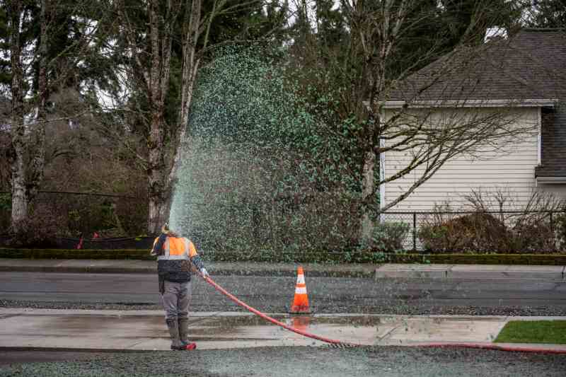 Professional hydroseeding, workman spraying a mix of grass seed and wood pulp from a big hose onto a freshly prepared dirt