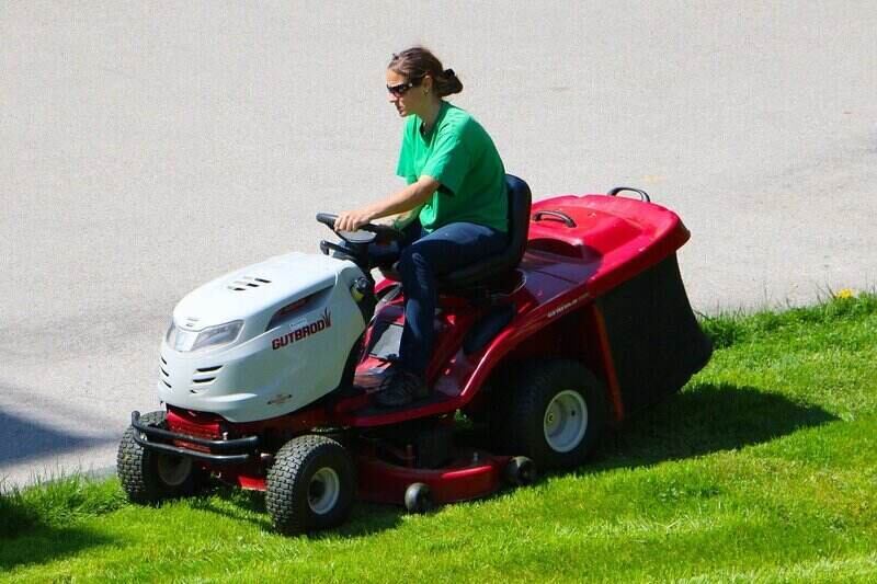 Woman in green T-shirt on a riding lawn mower