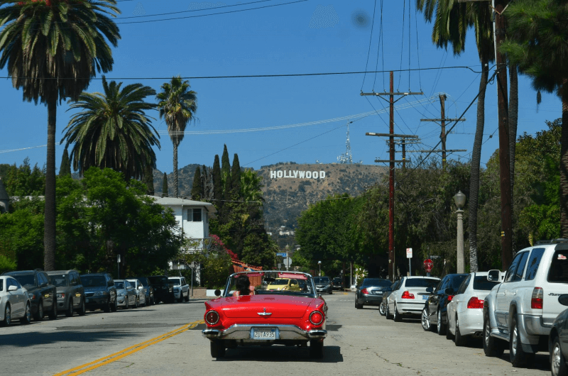 Red car on the road, overlooking the Hollywood sign