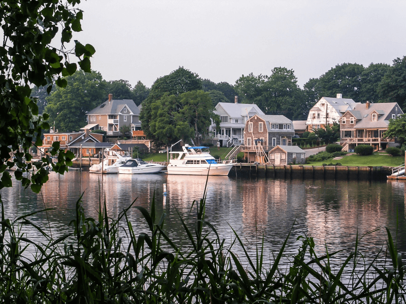 Small yachts float by coastal huts along the water in Warwick, Rhode Island