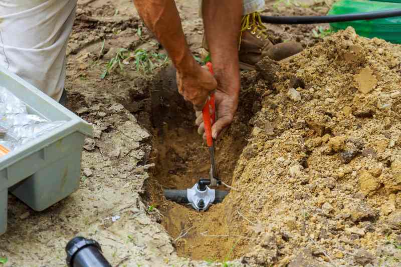 Underground Sprinkler System to Water the Yard Man Working with Pipes in Ground