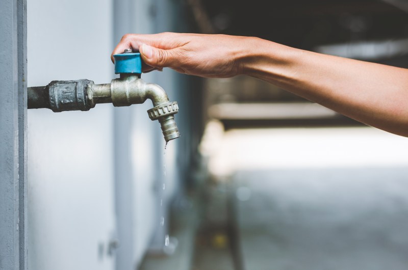 Woman's hand operating outdoor faucet