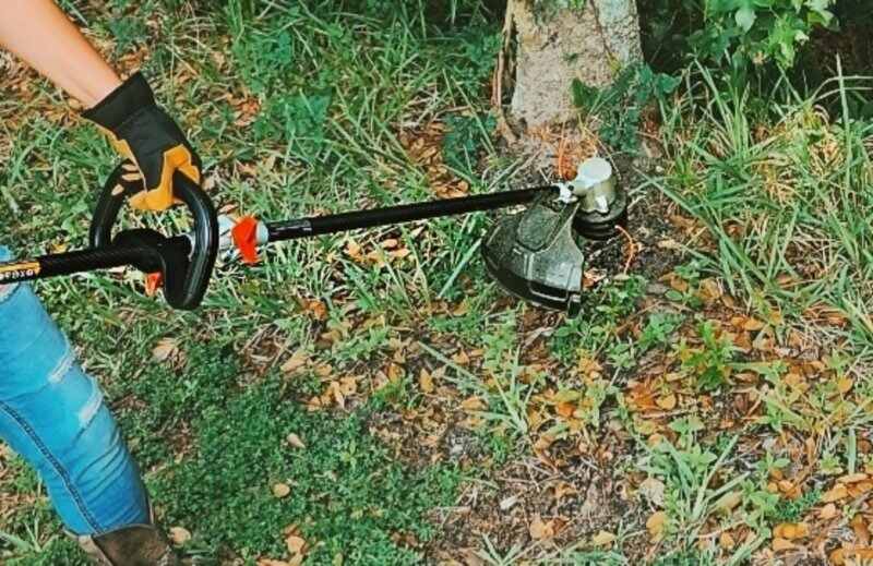 person using a string trimmer in lawn