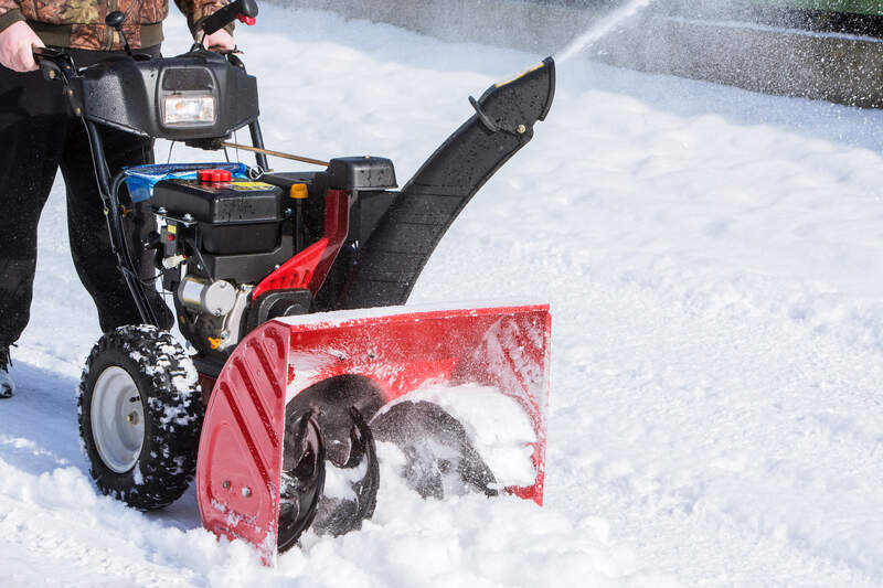 person using a two-stage snowblower to remove snow