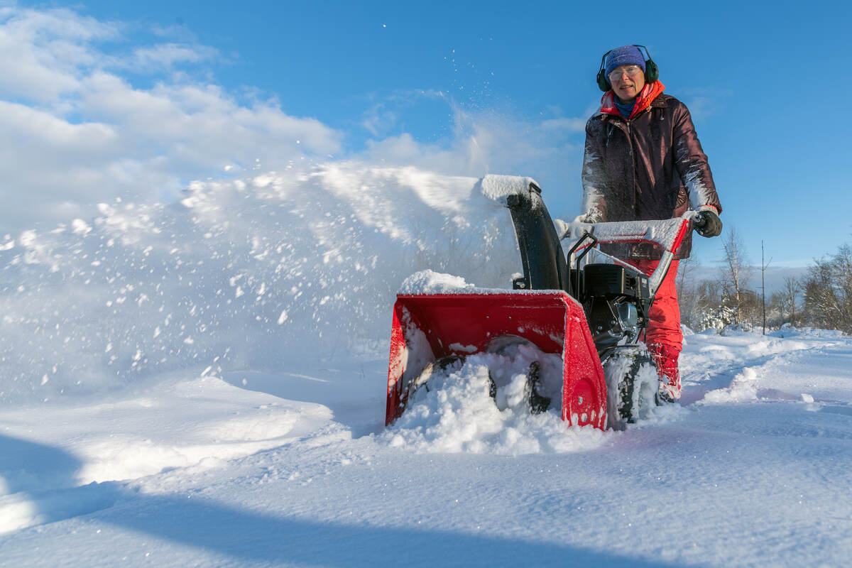 woman using a snow blower on a sunny winter day