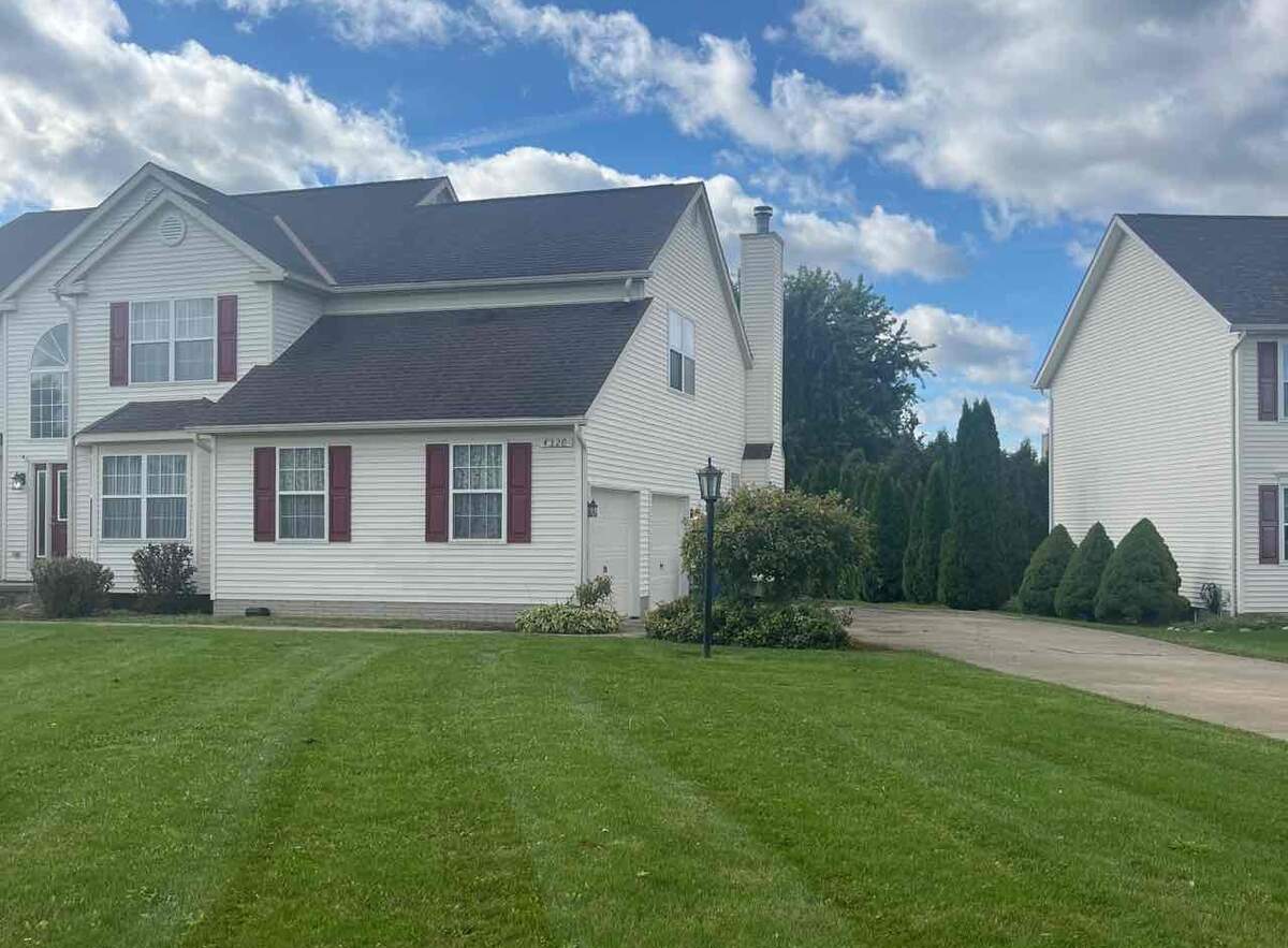 landscaped lawn in front of a house in Akron with a blue sky with clouds