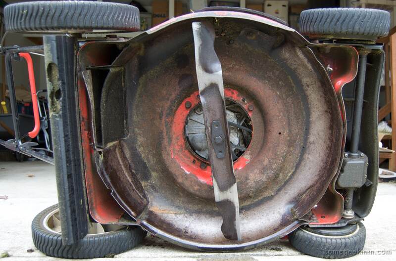 lawn mower tilted on its side with the camera looking at the underside and blade